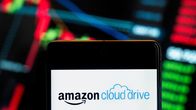 Amazonin omistaman amerikkalaisen tiedostojen isännöintipalveluyrityksen Amazon Cloud Driven logo älypuhelimella ja taustalla talousindeksikaavio.