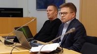 Kaksi miestä istuu pöydän takana, pöydällä edessä läppärit.