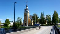 Gul träkyrka vid en älv.