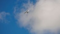 Hornet kaartaa nousun jälkeen sinistä taivasta vasten laskutelineet vielä alhaalla.