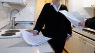 Kiinteistönvälittäjä ja asunnonkatsoja tutkii asunnon tietoja papereista.