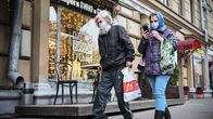 Mies ja nainen kulkevat ostoskadulla kauppakasseineen  ja maskit kasvoillaan