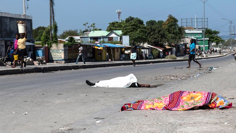 Döda människor ligger under skynken på en gata i Port au Prince i Haiti efter en attack av gängmedlemar.