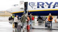 Matkustajat nousevat Ryanairin lentokoneeseen märällä lentokentällä.
