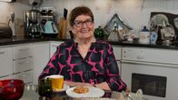 Maija Anttila istuu kahvipöydässä keittiössään.