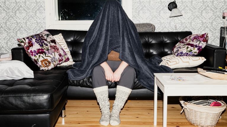 Henkilö istuu viltti päällä.