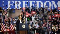 Kamala Harris i en talarstol med publik och en stor banderoll där det står "frihet" bakom henne. 