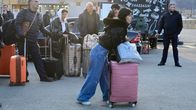 Människor med stora resväskor står i en klunga.