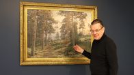 Mies tutkii vanhaa maisemamaalausta.