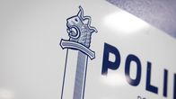 Sinivalkoiset poliisin miekkatunnus ja poliisi-teksti seinän kyltissä.