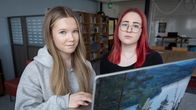 Kaksi pitkätukkaista nuorta läppärin äärellä koulun kirjastossa.