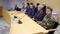 Oikeussalissa yhdeksän henkilöä istumassa pöydän takana.