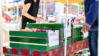 Mansikanmyyntikoju Tampereen Tammelantorilla. Asiakas juuri ostamassa myyjältä mansikoita.