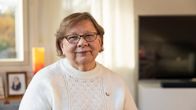 Vaaleaan neuleeseen pukeutunut Anneli Valtonen katsoo kameraan.