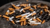 Close up of a dirty ashtray covered in burnt-out cigarette butts.