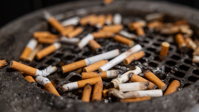 Close up of a dirty ashtray covered in burnt-out cigarette butts.