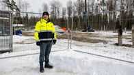 Mies seisoo työmaan vieressä työmaa-aidan ulkopuolella keltaisessa huomiotakissa. 