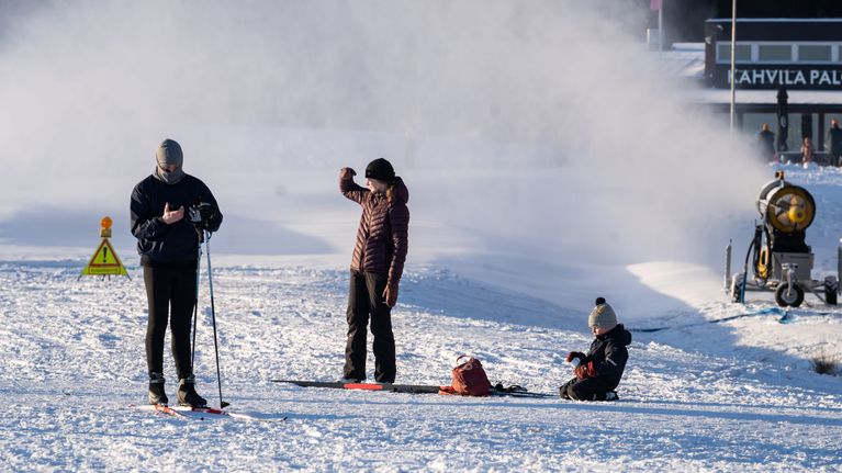 Ulkoilijoita latukoneen lähellä.