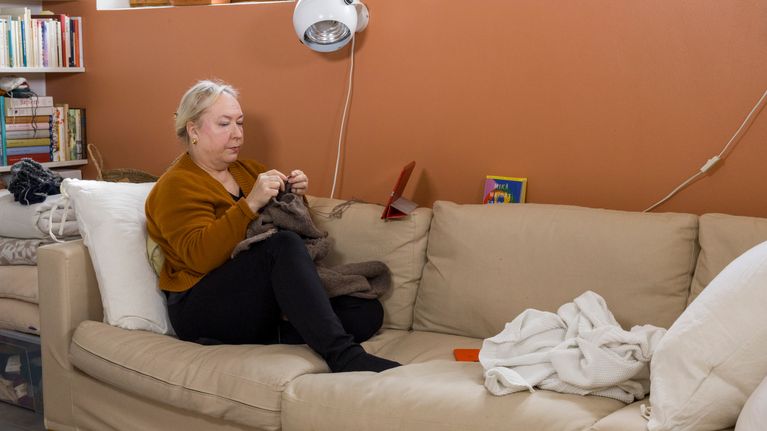 Marjo Nevalainen kotisohvallaan kutomassa. 