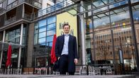 Mies seisoo liikerakennuksen edustalla kaupungin keskustassa.