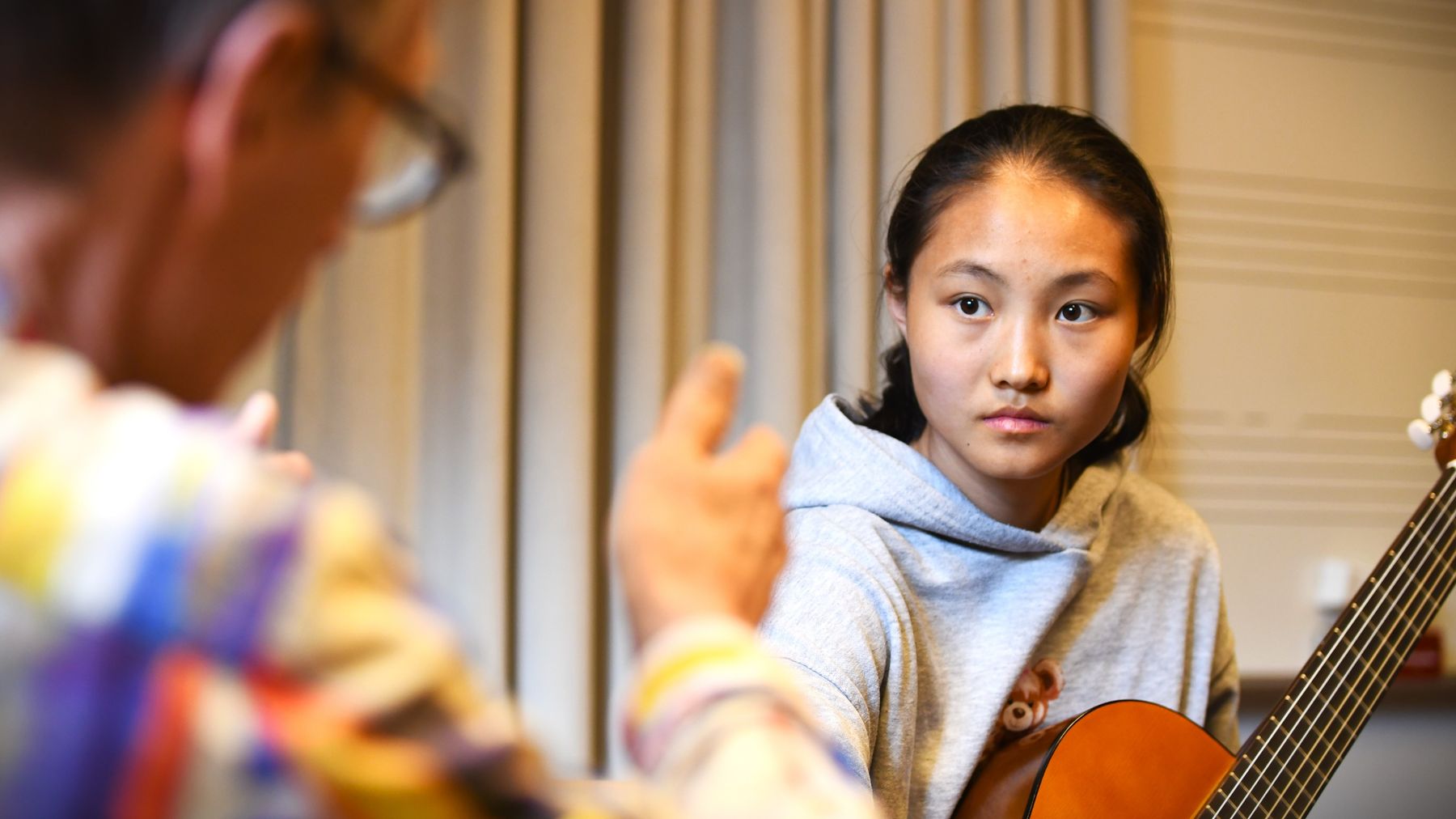 Queenie Xiang lyssnar på sin gitarrlärare Kari Jämbäck som syns i bildens ytterkant.