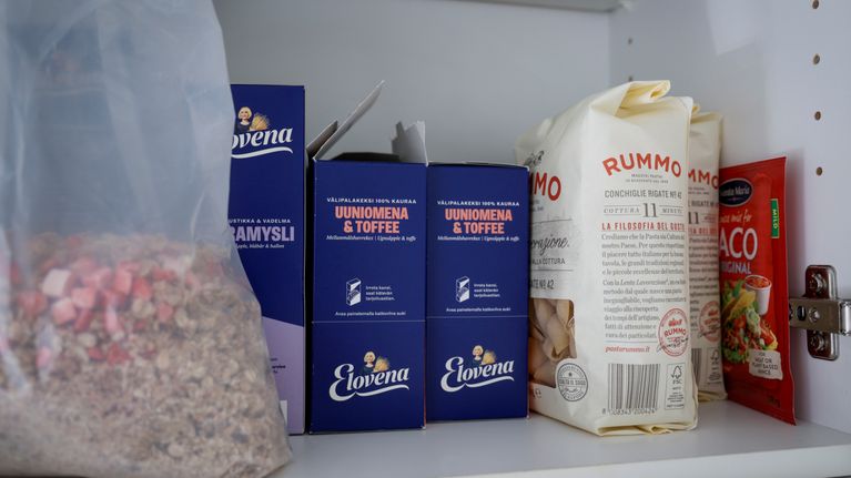Avoimessa kaapissa Elovena-pakkauksia, Rummo-makaronipusseja, taco-mausteseos ja muovipussissa mysliä.