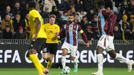 Fyra fotbollsspelare i gult och vinrött spelar på en plan inför publik, texten "UEFA CONFERENCE LEAGUE" syns i bakgrunden.