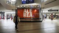 The entrance to Stockmann department store in a shopping mall, with a person wearing a face mask walking in the foreground.