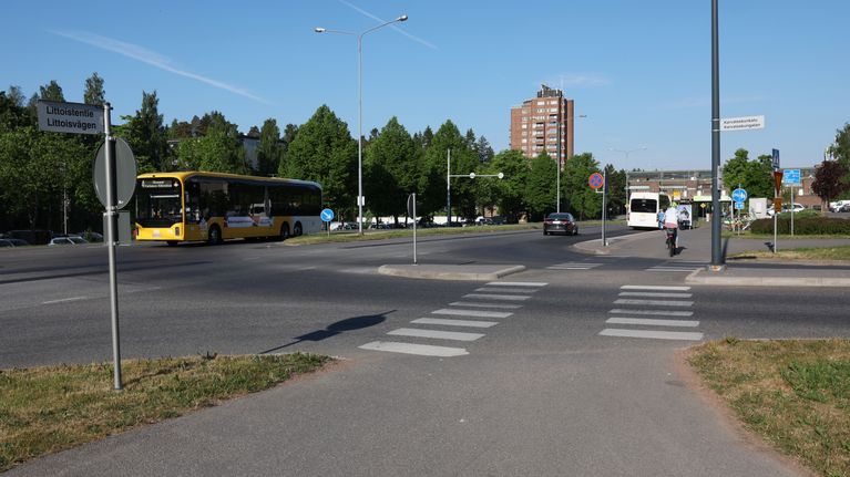 A pedestrian crossing with a couple of buses and cars seen in the background. 
