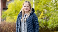 Lina Lignell står utomhus vid en grön buske.