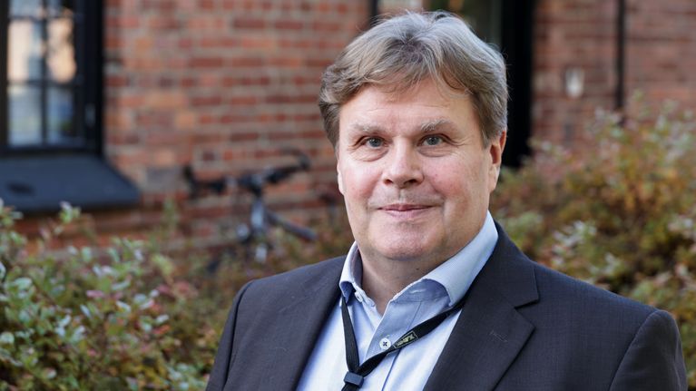 Mika Ruponen seisoo punaisen tiilitalon edustalla Kaakkois-Suomen ammattikorkeakoulun Mikkelin kampuksella.