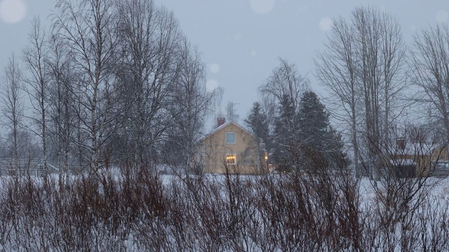 Talvinen maisema, jossa taustalla näkyy keltainen talo lumen peittämän metsän keskellä.
