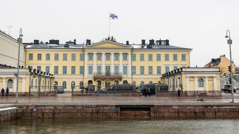 Presidentens slott, en ljusgul byggnad vid ett hamnområde med vita pelare och en stor balkong. på framsidan  