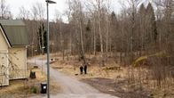 Tyhjä tontti hiekkapohjaisen kevyenliikenteenväylän vieressä, tien toisella puolella keltainen omakotitalo.