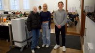 Nuoret opiskelijat seisovat kuvassa ja takana näkyy muita oppilaita.