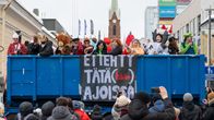 Joukko nuoria kuorma-auton kyydissä naamiaisasussa. Kuvan alalaidassa yleisöä seuraamassa kulkuetta. Kuorma-autoon kiinnitetyssä lakanassa teksti "ei tehty tätä(kään) ajoissa".