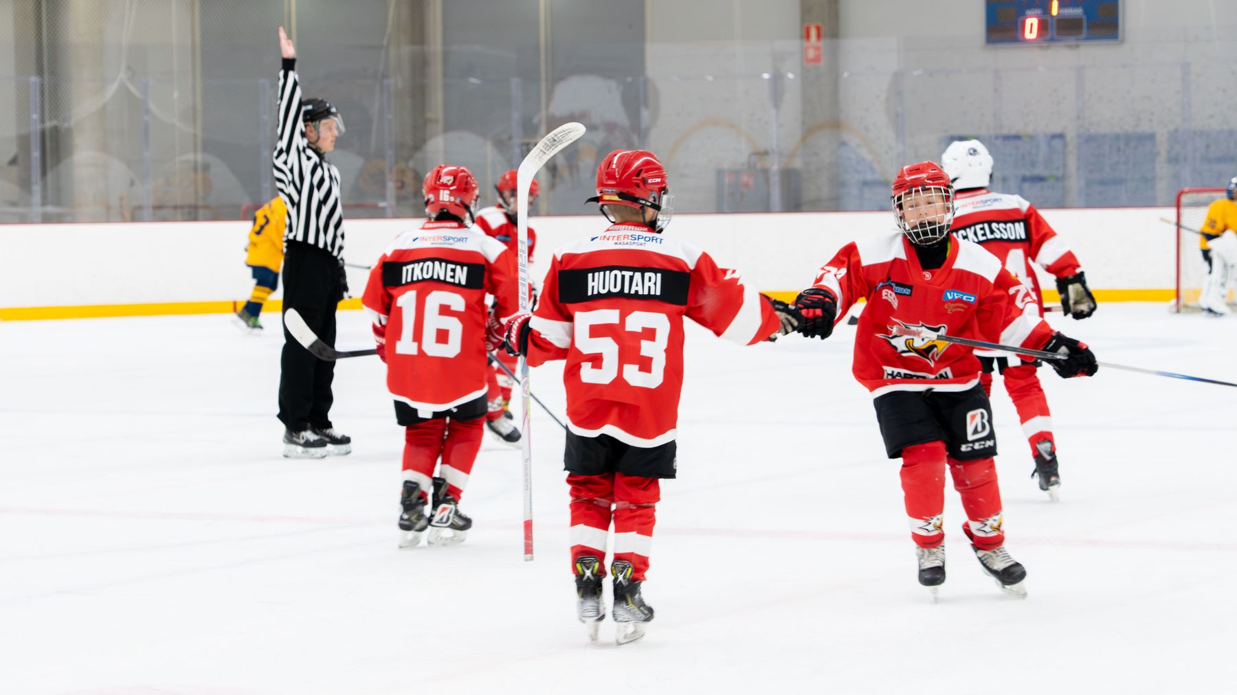 Det här är en bild av en ishockeymatch där spelare klädda i röda tröjor firar ett mål. En domare har handen uppe och signalerar ett mål. 
