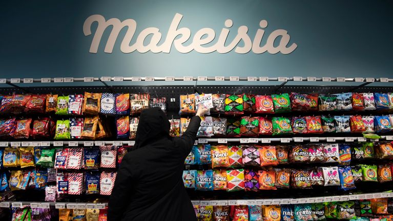 Asiakas makeishyllyn edessä ruokakaupassa.