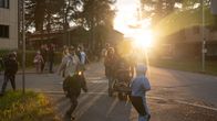 Lapset ja vanhemmat kadulla lämpimässä auringonlaskussa.