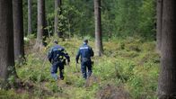 Kaksi poliisia kävelee maastossa.
