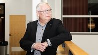 Keski-Suomen hyvinvointialueen arviointiryhmän puheenjohtaja, lääketieteen tohtori Jaakko Herrala nojaa puiseen kaiteeseen.