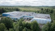 Ilmakuva tehdashallista metsämaisemassa.