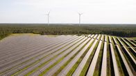 Aurinkopaneeleita aurinkopuistossa. Taustalla näkyy tuuliturbiineja. Solarigo Systems Oy:n aurinkopuisto Kalajoella Pohjois-Pohjanmaalla.