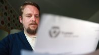 Iiro Lehtiö katselee TE-toimistolta saamaansa kirjettä kotonaan keittiön pöydän ääressä.