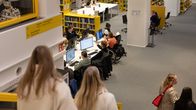 Yliopiston kirjaston asiakkaita kirjaston alakerrassa ja portailla. 