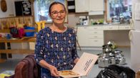 Ritva Kangasniemi hymyilee kameralle ja pitelee käsissään lastenkirjaa vanhassa kielipesässä syyskuussa 2025.