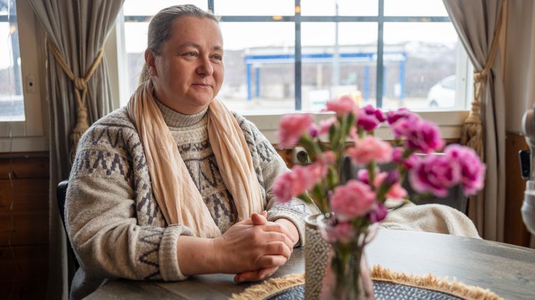 Utsjoen kunnanjohtaja Päivi Kontio istuu sisätiloissa pöydän ääressä, jonka päällä on maljakollinen kukkia.