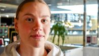 Saga Vanninen seisoo sisätiloissa urheilullisessa hupparissa, jossa näkyy useiden yritysten logoja.