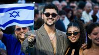 Mies aurinkolaisessa ja puvussa heiluttaa Israelin lippua kameralle.