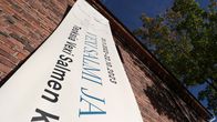 Vexi Salmen muistonäyttelystä kertova mainoslakana alaviistosta kuvattuna punatiilisen rakennuksen seinässä.